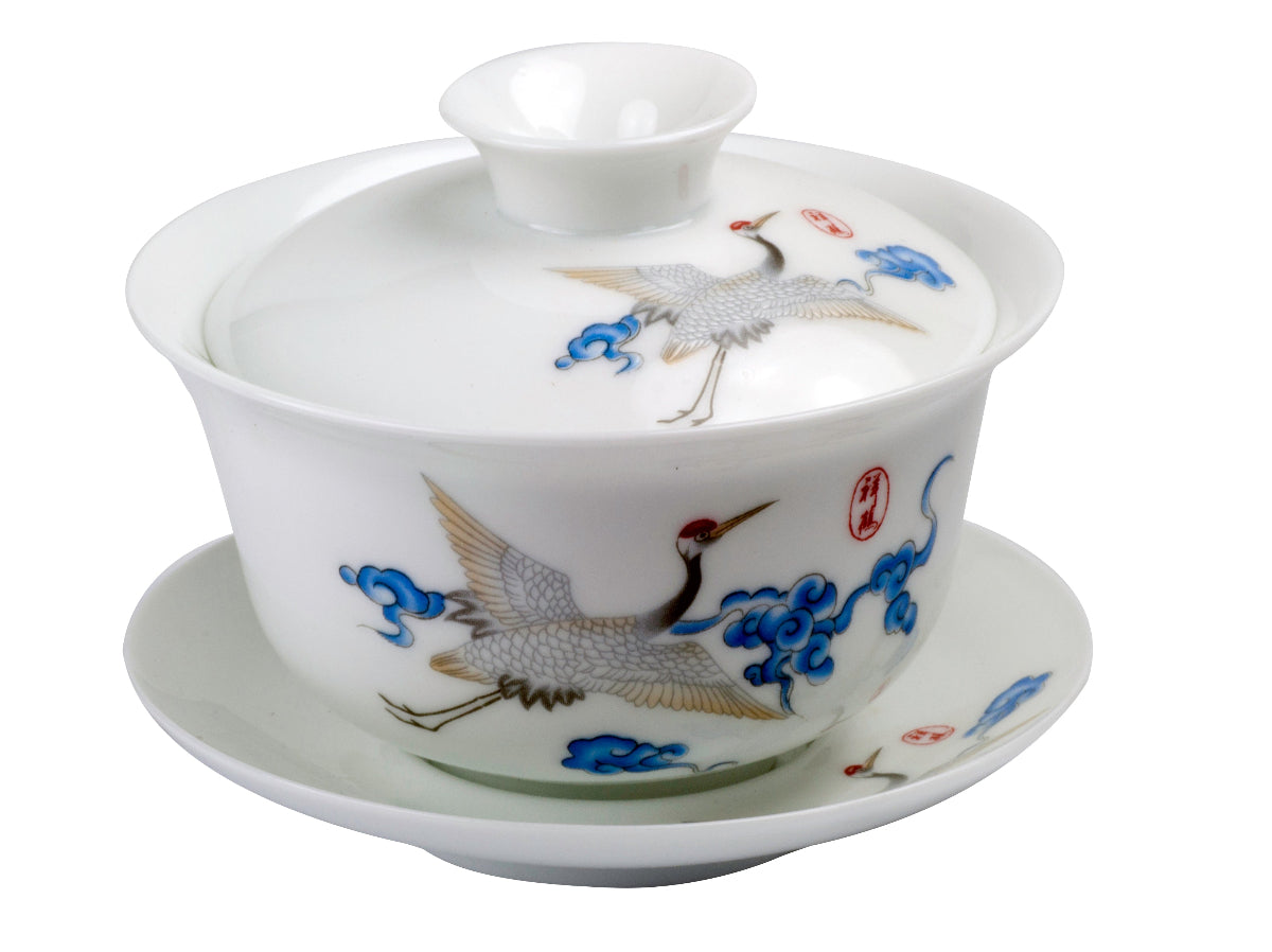A white porcelain Gaiwan with blue and red bird patterns, including a lid and a saucer.