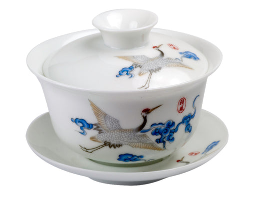 A white porcelain Gaiwan with blue and red bird patterns, including a lid and a saucer.